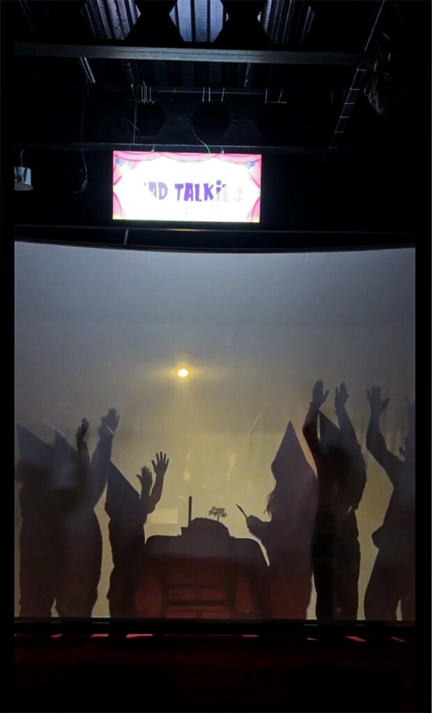 Children performing a shadow play with raised hands during a birthday celebration at MAD Labs’ Mad Talkies zone.