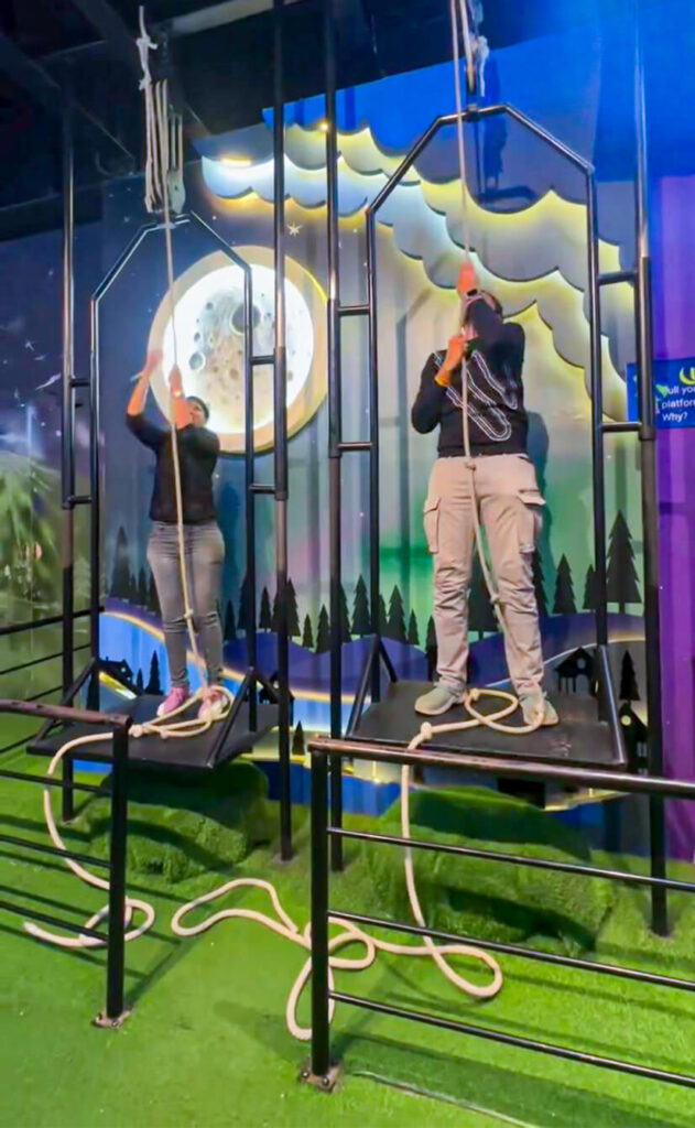 Visitors trying the gravity challenge activity with pulleys at MAD Labs