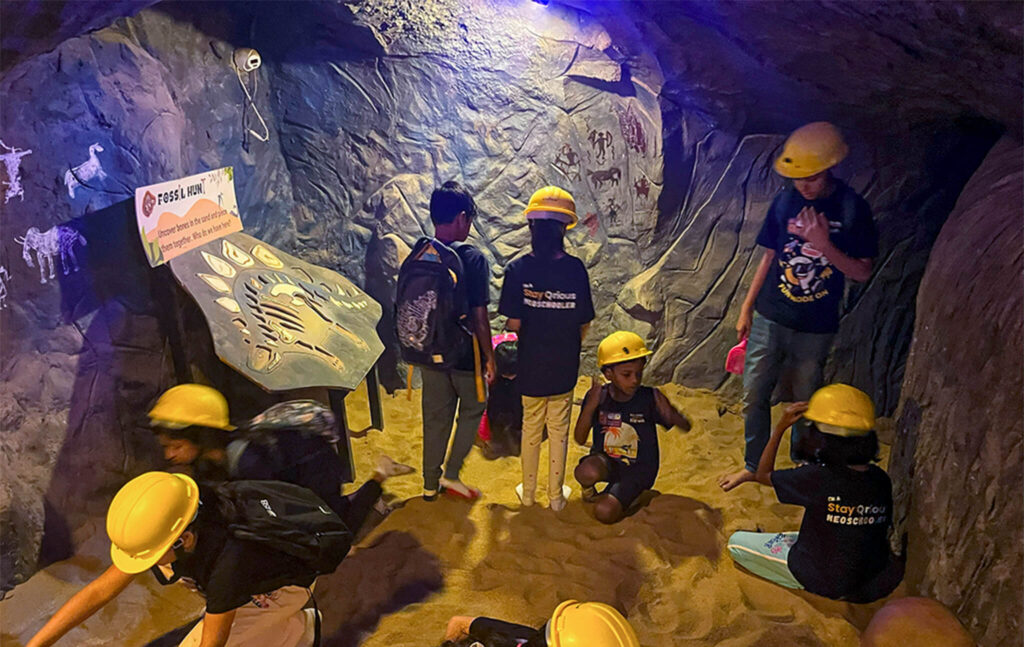 Children with helmets exploring Fossil Hunt cave activity at MAD Labs