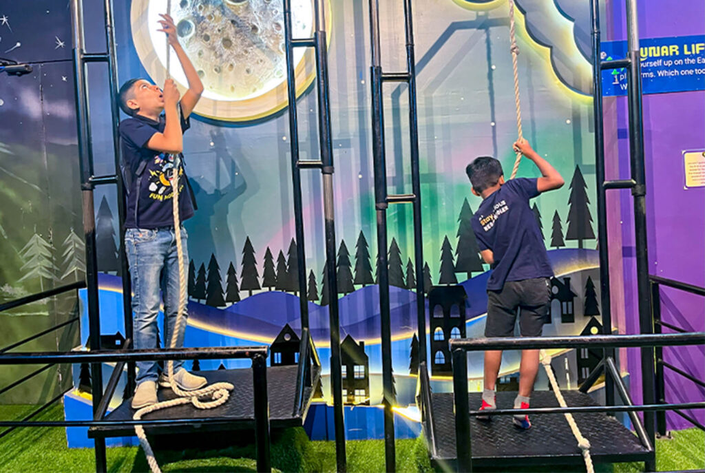 Kids trying the Lunar Lift pulley challenge activity at MAD Labs