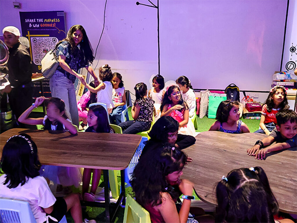 Children seated at tables during a birthday party activity session inside MAD Labs, Bangalore.