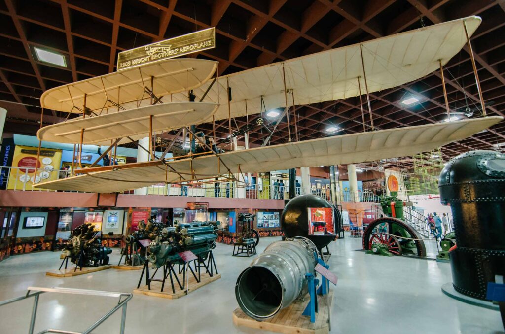 Exhibit of the 1903 Wright Brothers Aeroplane at Visvesvaraya Industrial and Technological Museum in Bangalore, showcasing historic engines and machines.